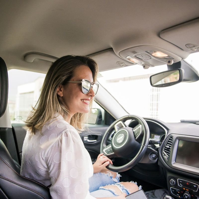 Mulher sorrindo ao volante de um carro