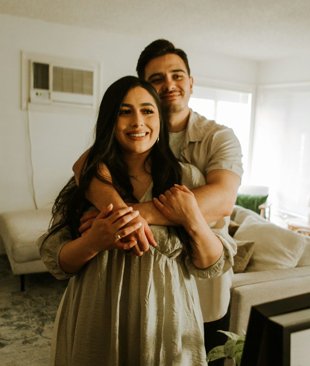 Casal sorrindo e abraçado na sala da casa nova