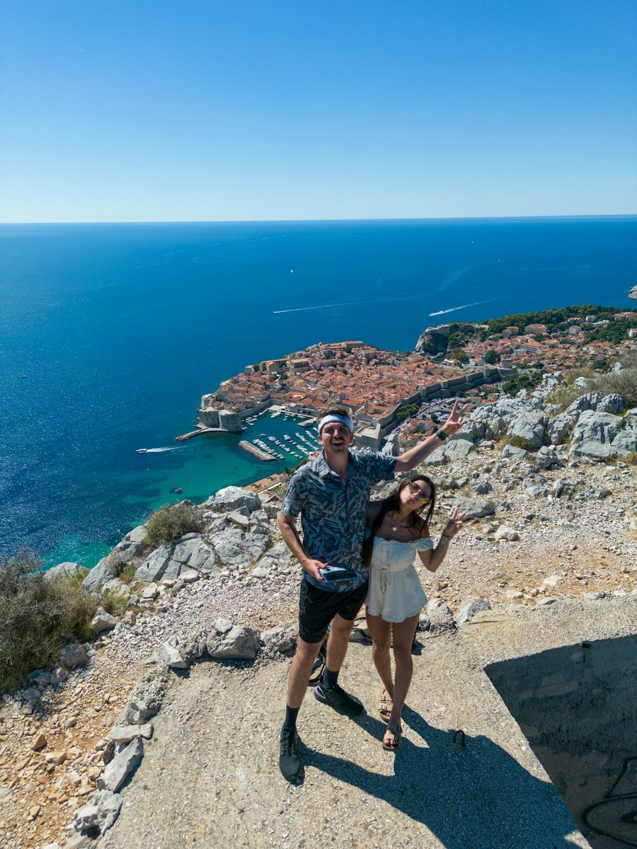 Casal de braços abertos em um mirante sobre o mar